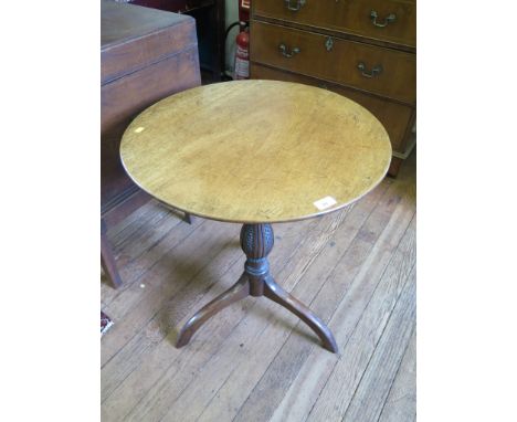 A George III mahogany snaptop tripod table, the circular top over a scale carved baluster stem on downswept tripod legs, 61cm