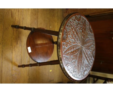 A carved wood tripod table, the circular top carved with flowers and lunette's on turned legs joined by an under shelf, 40cm 