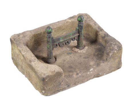 A limestone and cast iron boot scrape, early 19th century, cast with pinecone shaped finials and scrolls, above a rough-hewn 