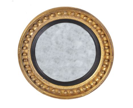 A Regency giltwood convex wall mirror, circa 1815, by Thomas Fentham, the oval mirror plate within a reeded ebonised slip, th