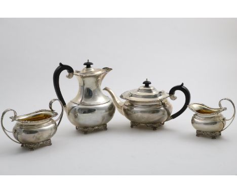 A GEORGE V FOUR-PIECE TEA SERVICE with rounded rectangular bodies, winged paw feet and borders of gadrooning with foliate she