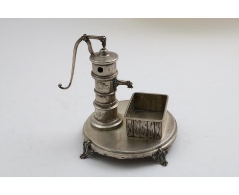 A 19TH CENTURY GERMAN NOVELTY SMOKER'S COMPENDIUM  in the form of a water pump and trough on a circular base, a long looping 