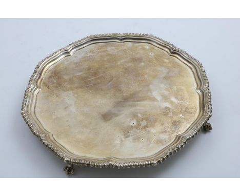 A GEORGE V SALVER of shaped circular outline with a gadrooned border and ball &amp; claw feet, by Harrison Brothers &amp; How