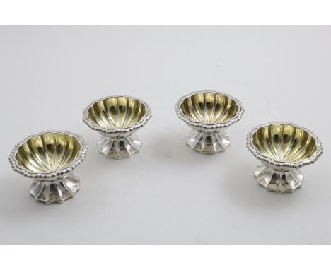 A SET OF FOUR GEORGE IV SALTS with fluted circular bowls, gadrooned rims &amp; fluted pedestal bases, crested, by R. Emes &am
