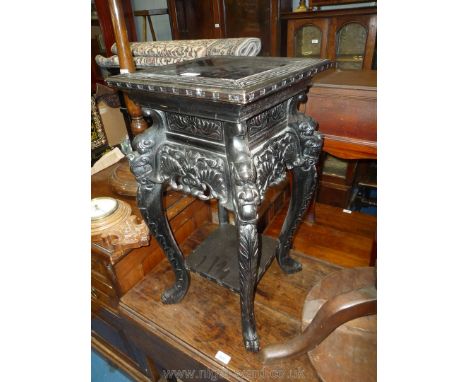 An ebonised chinsoserie urn/lamp Stand/Table having four legs with carved decoration including lion dog masks and united by a