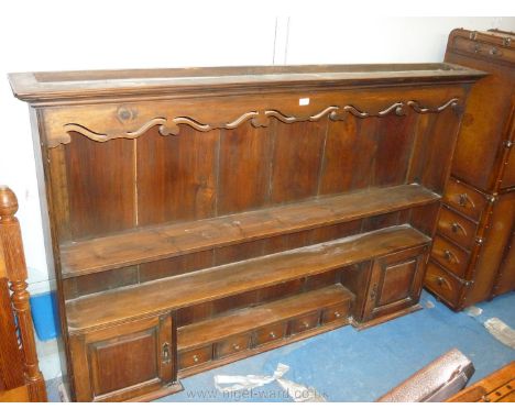 An Oak Dresser Rack with fretworked frieze and incorporating a pair of cupboards with raised and fielded doors, and five spic
