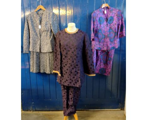 Three vintage ladies outfits to include: a purple floral brocade tunic with gold trim with matching trousers, purple floral p