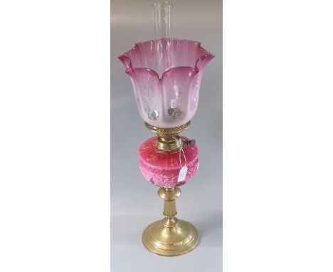 Early 20th Century double oil burner lamp having cranberry frosted glass shade above a pink floral reservoir on brass base. (