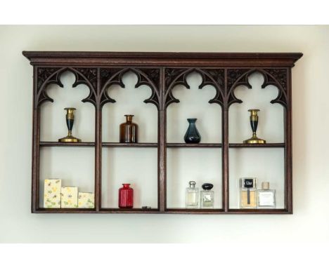 An oak gothic revival hanging wall shelf, 19th century, the two open shelves behind four arches with floral carved spandrels 
