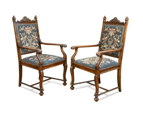 A pair of Continental walnut framed elbow chairs, early 20th century, with needlepoint tapestry backs and seats, the carved u