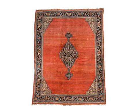 A Sarouk Feraghan carpet, circa 1930, with central indigo medallion on a plain terracotta field, ivory spandrels and deep ind