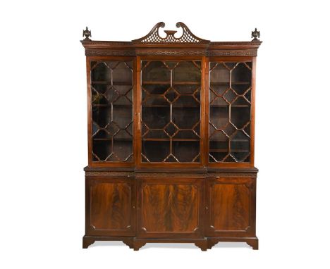 A George III style mahogany breakfront bookcase, late 19th century, the pierced broken swan neck pediment over a fret cut fri