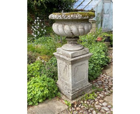 A reconstituted stone garden planter, late 20th century, of gadrooned body on a square plinth base70cm diameter, 133cm high