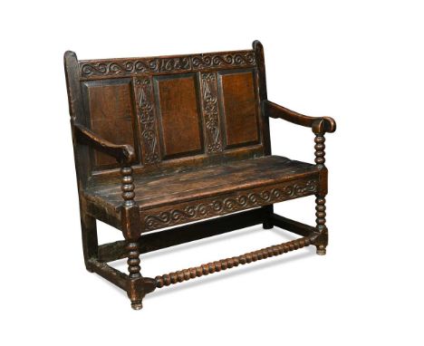 A small carved oak panel back settle, late 17th century, the carved top rail dated 1682, over three fielded panels and boarde