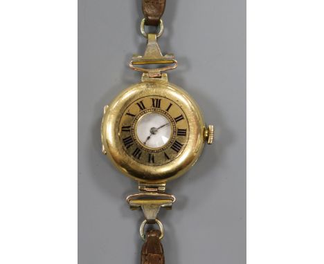 An 18ct. gold half hunter manual wind wrist watch, on a leather strap.