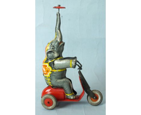 A just-post-WWII German tinplate clockwork elephant riding a tricycle, with a spinning top on the end of his trunk, marked "G