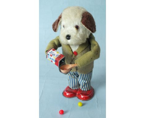 A Japanese tinplate clockwork dog eating candy sweets, with plush head, felt coat and fabric trousers, (c/w mechanism works b