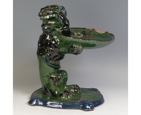 A C. H. Brannam pottery grotesque Centrepiece, modelled by Frank Thomas as an upright seated lion holding a plate, decorated 