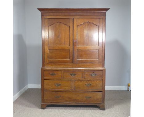 A Georgian oak housekeepers Cupboard, the moulded cornice over moulded doors enclosing shelves, raised on drawers and shaped 