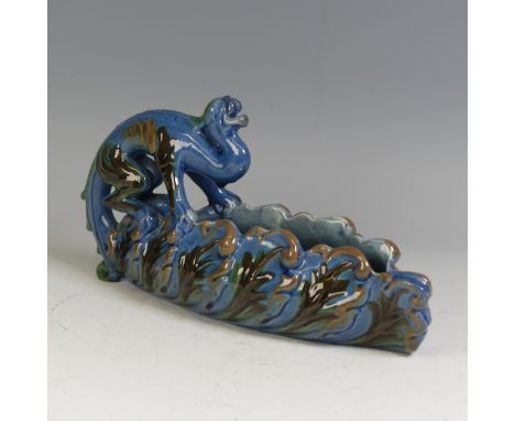 A C. H. Brannam pottery grotesque boat Dish, perched upon by a mythical figure, decorated in blue ground with green and brown