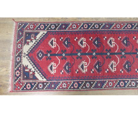Tribal rugs; a Turkish runner, red ground woven with 'Tree of Life' design in blue and cream,100% wool, pile worn in places, 
