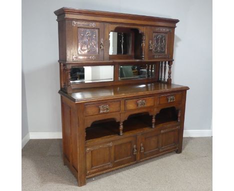 An Arts and Crafts oak Sideboard, the upper section with moulded cornice over central mirrored shelf, flanked by cupboards to