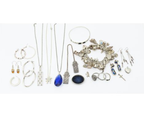A vintage silver charm bracelet, suspending various charms including violin, bird cage, kitten, suit case etc, along with rin