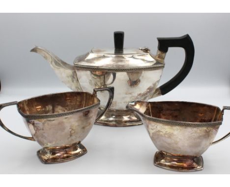 An Elizabeth II Art Deco style three piece tea set, of angular shape with curved bases, tea pot with ebonised handle and fini