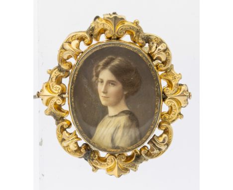 An antique yellow metal ivory miniature mourning brooch, depicting a glazed an oval portrait of a young woman, within a decor