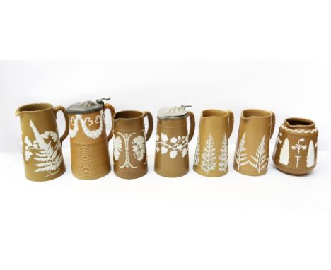A collection of seven Dudson brown jugs, all with various white relief designs, all not stamped Dudson but with other marks, 