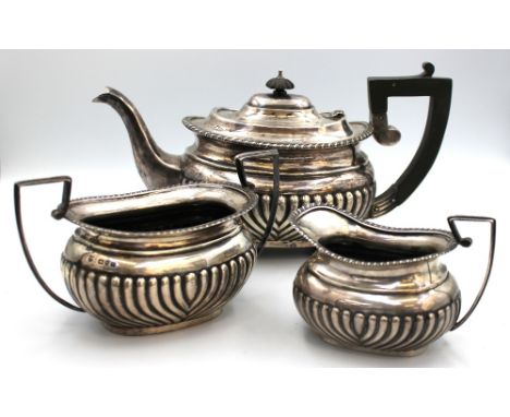 A matched late Victorian silver three piece tea set, all of oblong shape with gadrooned lower bodies, tea pot with ebonised f