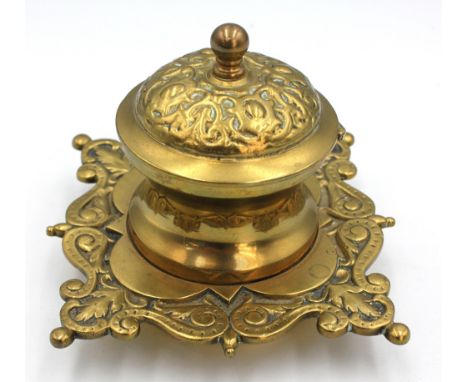 A 20th century brass inkwell, elaborately shaped with scrolled form, hinged domed-shape cover revealing glass liner, unmarked