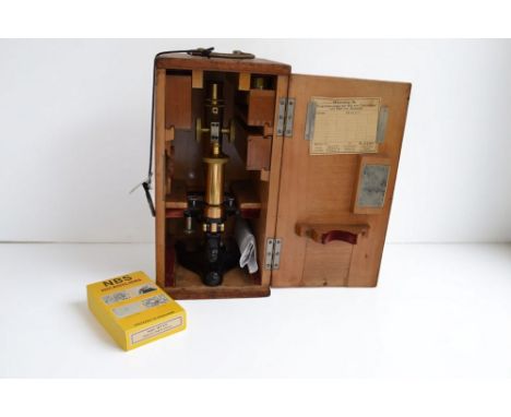 An E. Leitz Wetzlar brass microscope, in original wooden carry case with hinged door, with a box of NBS Microslides and some 