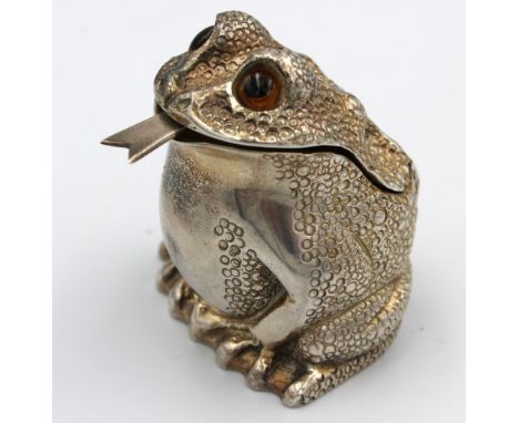 A novelty Elizabeth II silver mustard pot, realistically modelled as a frog, having glass eyes and matching spoon forming the