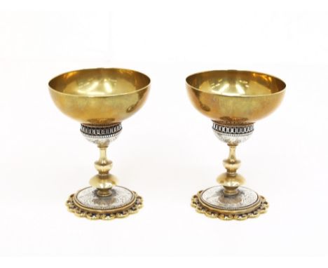 A pair of late 19th / early 20th century, probably North African brass and silver centred goblets, raised upon an engraved si