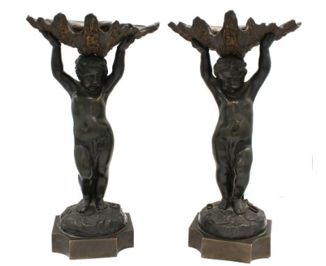 A pair of 19th century, possibly French cast bronze figural comports; each cast in the form of cherubs holdings shells above 
