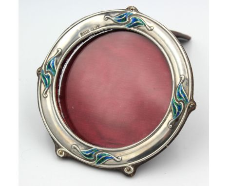 An Edwardian Art Nouveau silver and enamel circular shaped photo frame, having leather easel back and silver mount decorated 