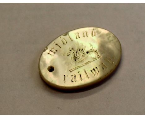 An oval 33 x 25mm mother of pearl Midland Railway free ticket token with hole for suspension. Engraved ‘midland railway’ with
