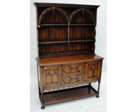 A 1920s oak dresser, the boarded arcaded back above a base of two drawers flanked by cupboard doors on rope twist supports to