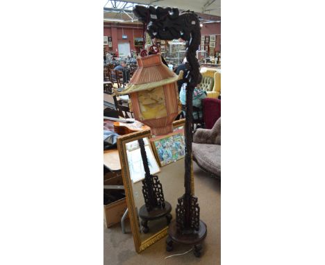 A carved hardwood standard lamp, the main stem decorated with a stylised dragon above a pierced and circular base, complete w