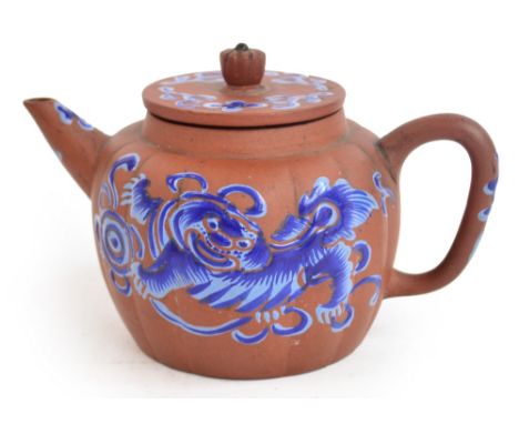 An 18th/19th century Chinese Yixing teapot of lobed globular form, painted in blue enamels with Buddhist lions and floral spr