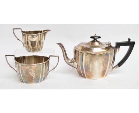 A George V hallmarked silver three piece tea service of shaped oval form, teapot with black ebonised handle and finial, Sheff
