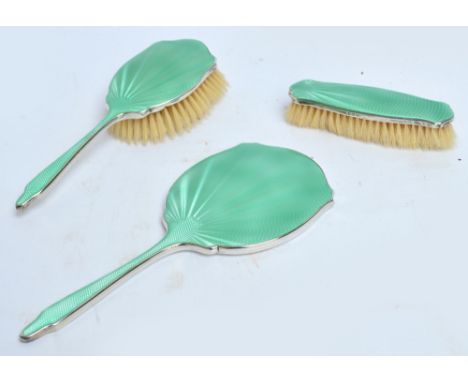 A George V hallmarked silver and green guilloche enamel backed Art Deco three piece dressing table set, comprising hand mirro