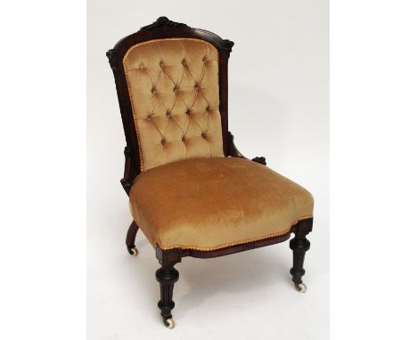 A late Victorian walnut framed button upholstered ladies chair raised on ring turned fluted front legs to castors.