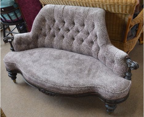 A Victorian ebonised settee, the button upholstered scroll padded back with carved scrolling arms above serpentine set raised