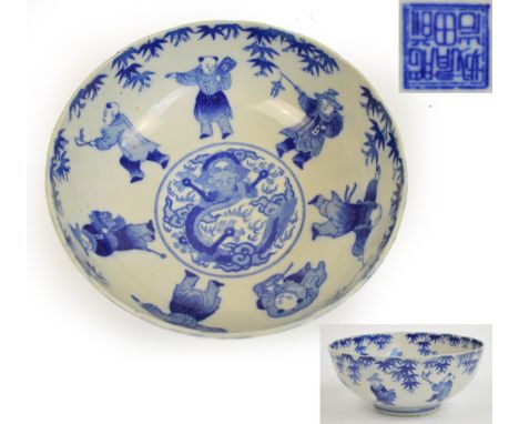 A decorative 20th century Chinese porcelain bowl decorated with boys around a central dragon within a border of bamboo sprays