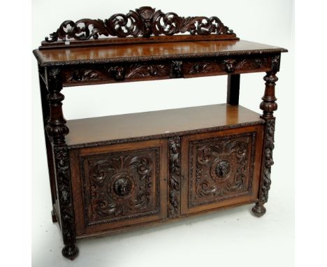 A late Victorian carved oak buffet, the carved top rail above two frieze drawers and base of two cupboard doors flanked by fl
