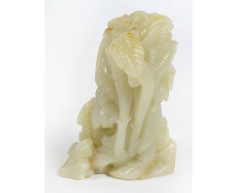 An early 19th century Chinese pale green jade carving depicting Guanyin beneath a palm tree, the leaves with slight russet in