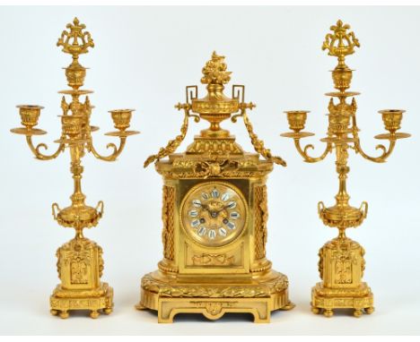 A late 19th century French gilt metal clock garniture, the urn surmounted clock with circular dial set with Roman numerals to