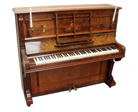 A walnut inlaid cased over strung upright piano by R. Fietze, Berlin, with twin brass candle sconces.